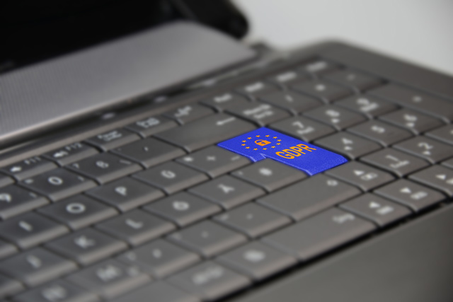 Black laptop keyboard. Enter key is bright blue and has a word GDPR on it. All other keys are fuzzy.